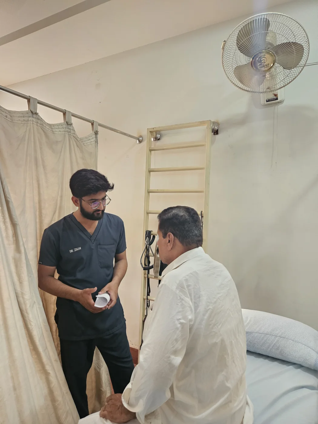 Clinical physiotherapist assessing a patient beside wall bars during a consultation